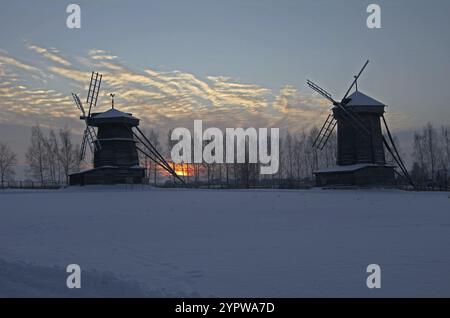 Soirée d'hiver. Le soleil se couche entre deux moulins à vent. Musée d'architecture en bois, Souzdal, Russie, Europe Banque D'Images