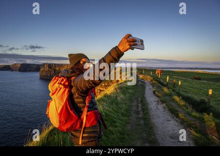 Femme randonneur prenant un selfie, Cliffs of Moher, The Burren, County Clare, Irlande, Royaume-Uni, Europe Banque D'Images