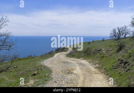 Un chemin de terre longeant une montagne déserte sur le bord de la mer. Cap Meganom, Crimée, une journée ensoleillée en avril Banque D'Images