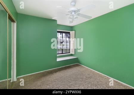 Petite chambre vert vif avec moquette, moulures et fenêtres. Chambre lumineuse, intérieurs Banque D'Images