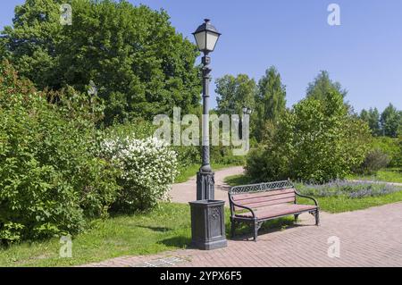 Un coin confortable dans le parc, une lanterne, un banc et un buisson orangé en fleurs. Parc Tsaritsynski, Moscou, Russie. Journée ensoleillée en juin Banque D'Images