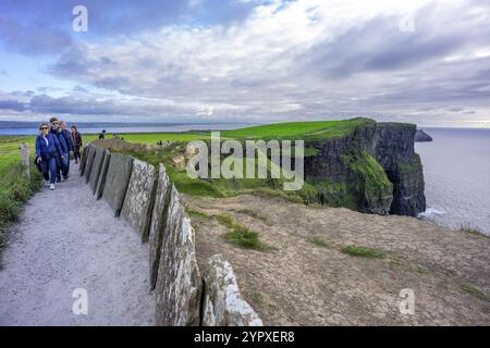 Randonneur entre clôture traditionnelle en pierre, falaises de Moher, le Burren, comté de Clare, Irlande, Royaume-Uni, Europe Banque D'Images