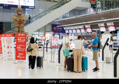 Bangkok, Thaïlande - 22 novembre 2024 : enregistrement familial de tourisme dans le distributeur de billets d'avion en libre-service et femme voyageuse allant au départ de la porte d'embarquement au suv Banque D'Images