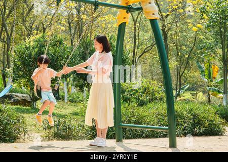 Mère et fils se balançant dans le parc Banque D'Images