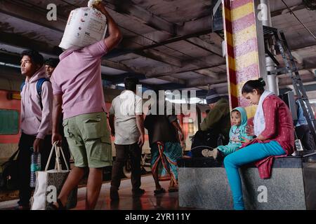 Passagers ferroviaires sur un quai à la gare de Dadar à Mumbai, en Inde, portant des sacs à droite : une mère qui attend avec son petit enfant Banque D'Images