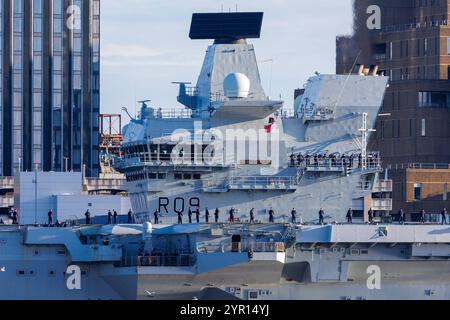Le porte-avions HMS Prince of Wales de la Royal Navy arrive à Liverpool, avec un équipage debout sur le pont et l'emblématique skyline de la ville à l'arrière Banque D'Images