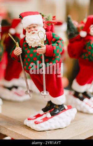 Un père noël avec des skis aux pieds. Il porte un pull vert. Il tient un sac. Pologne, Varsovie 01.12.2024 Banque D'Images