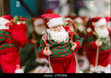 Un père noël avec des skis aux pieds. Il porte un pull vert. Il tient un sac. Pologne, Varsovie 01.12.2024 Banque D'Images