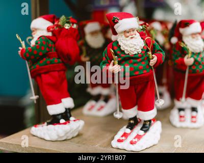 Un père noël avec des skis aux pieds. Il porte un pull vert. Il tient un sac. Pologne, Varsovie 01.12.2024 Banque D'Images