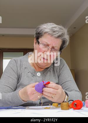 Une femme senior engagée dans l'artisanat, axée sur le tricot avec du fil coloré. Elle respire la concentration et aime le processus tactile de création de handma Banque D'Images