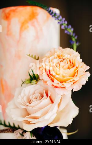 Gros plan du gâteau de mariage avec la coloration pêche marbrée et les fleurs de rose Banque D'Images
