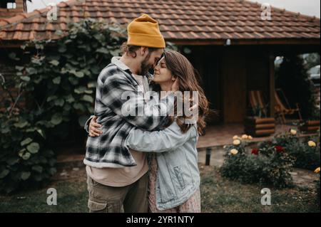 Heureux jeune couple serrant dans le jardin de leur maison de village. Banque D'Images