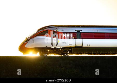 Un train Azuma LNER (800102), rétroéclairé par Un coucher de soleil, alors qu'il voyage entre Dalmeny et Edinburgh Gateway stations Scotland UK Banque D'Images