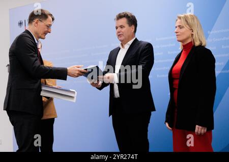 02 décembre 2024, Berlin : Karl Lauterbach (SPD), ministre fédéral de la santé, remet le plan d'action pour un système de santé diversifié, inclusif et sans obstacles à Jürgen Dusel (M), commissaire du gouvernement fédéral pour les questions relatives aux personnes handicapées, et Verena Bentele (R), porte-parole du Conseil allemand des personnes handicapées au ministère fédéral de la santé. Photo : Carsten Koall/dpa Banque D'Images