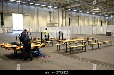 02 décembre 2024, Hambourg : des tables et des bancs sont installés lors de l'événement médiatique dans le logement des réfugiés du Hall B5 sur le terrain d'exposition, tandis que des cabanes d'hébergement temporaire sont visibles en arrière-plan. À partir du 3 décembre, le Hall B5 deviendra à nouveau un hébergement d’urgence pour les réfugiés. L'occupation est prévue pour jusqu'à 300 personnes, avec une capacité d'urgence totale de 476 places dans les compartiments. Le logement sera géré par l’entreprise sociale municipale Fördern & Wohnen. Photo : Niklas Graeber/dpa Banque D'Images