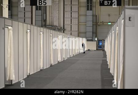 02 décembre 2024, Hambourg : un employé examine une rangée de cabines d'hébergement temporaire lors d'un rendez-vous avec les médias dans le logement des réfugiés dans le Hall B5 sur le terrain d'exposition. À partir du 3 décembre, le Hall B5 deviendra à nouveau un hébergement d’urgence pour les réfugiés. L'occupation est prévue pour jusqu'à 300 personnes, avec une capacité d'urgence totale de 476 places dans les compartiments. Le logement sera géré par l’entreprise sociale municipale Fördern & Wohnen. Photo : Niklas Graeber/dpa Banque D'Images