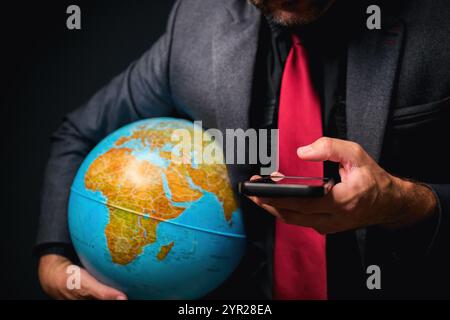 Concept d'affaires global, homme d'affaires utilisant un smartphone et tenant le globe terrestre dans les mains, focalisation sélective Banque D'Images