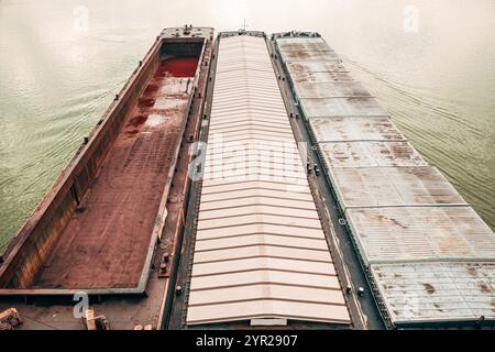 Une barge, bateau à fond plat, poussé par un remorqueur le long de la rivière pour le transport, vue en angle élevé Banque D'Images