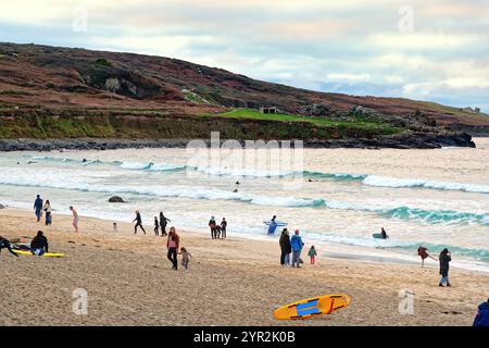 Porthmeor plage au crépuscule un jour d'automne avec quelques surfeurs robustes dans la mer St Ives Cornwall Angleterre Banque D'Images