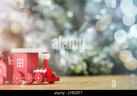 Train en bois de Noël jouet sur fond de neige, bokeh et arbre de Noël. Nouvel an et concept de Noël. Flou artistique léger. Banque D'Images