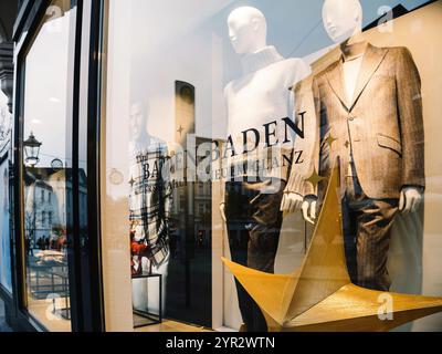 Baden-Baden, Allemagne - 1er décembre 2024 : devanture élégante à Baden-Baden avec des mannequins habillés dans une tenue d'hiver élégante, une décoration d'étoile dorée et des reflets de l'environnement urbain Banque D'Images