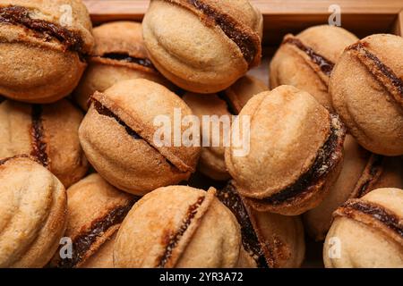 Biscuits en forme de noix sucrées avec du lait condensé bouilli dans une boîte en bois, gros plan Banque D'Images