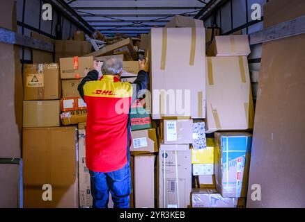 02 décembre 2024, Brandenburg, Rüdersdorf : un employé charge des colis et des colis dans la soute d'un camion au centre de colis DHL. Quelques semaines avant Noël, le service de livraison de DHL livre actuellement environ un demi-million de colis par jour dans la région de la capitale. Les volumes de colis pour Berlin et une grande partie du Brandebourg sont traités par les trois centres de colis DHL à Ludwigsfelde, Rüdersdorf et Börnicke. En conséquence, environ 32 000 envois par heure sont traités sur ces sites logistiques, et pas moins de 50 000 à Ludwigsfelde. Photo : Patrick Pleul/dpa Banque D'Images