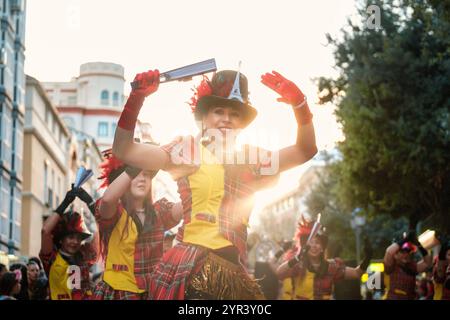 L'image représente une scène de rue animée avec un groupe de personnes vêtues de costumes colorés. La figure centrale est une personne souriante portant un chapeau Banque D'Images