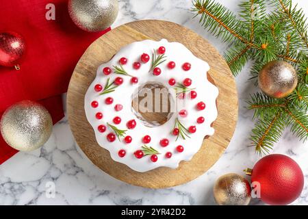 Gâteau de Noël joliment décoré, branches de sapin et boules sur la table en marbre blanc, plat Banque D'Images