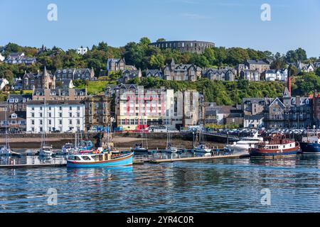 Port et front de mer d’Oban, avec la tour McCaig sur Battery Hill surplombant la ville, à Oban, Argyll et Bute, Écosse, Royaume-Uni Banque D'Images