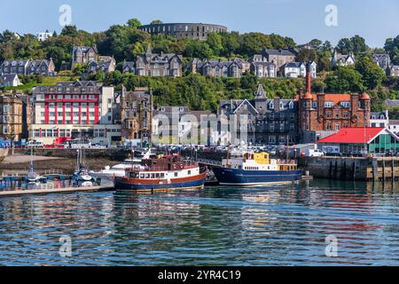 Port et front de mer d’Oban, avec la tour McCaig sur Battery Hill surplombant la ville, à Oban, Argyll et Bute, Écosse, Royaume-Uni Banque D'Images