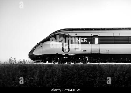 Image monochrome d'Un train Azuma LNER (800102), rétroéclairé par Un coucher de soleil couchant, alors qu'il voyage entre Dalmeny et Edinburgh Gateway stations Scotland UK Banque D'Images