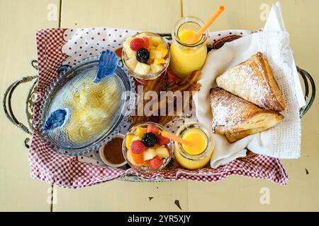 Panier petit déjeuner rustique avec viennoiseries, fruits frais et jus d'orange Banque D'Images