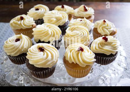 Cupcakes assortis avec glaçage crémeux tourbillon sur une assiette de service en verre Banque D'Images