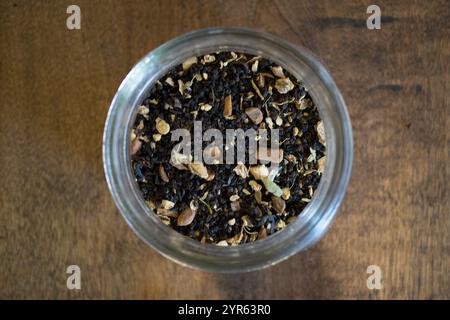 Vue de dessus du mélange de thé en feuilles en vrac dans un bocal en verre sur une surface en bois Banque D'Images