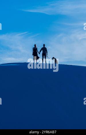 AVRIL 2021, WHITE SANDS NATIONAL PARK, NOUVEAU MEXIQUE, États-Unis - silhouette d'homme, femme et chien sur les dunes de sable du White Sands National Monument, Nouveau Mexique Banque D'Images