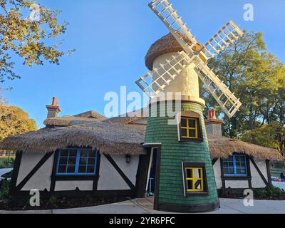 Un charmant moulin à vent avec un toit de chaume et des bardeaux verts se dresse dans un cadre pittoresque entouré d'arbres par une journée claire et ensoleillée. Banque D'Images