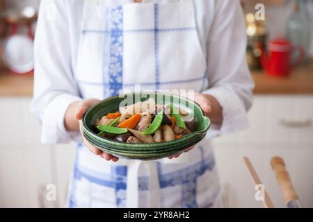 Femme tenant une assiette de chikuzen-ni sur une assiette Banque D'Images