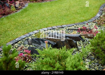 Un jardin magnifiquement luxuriant avec de superbes accents de pierre et une variété de flore vibrante Banque D'Images