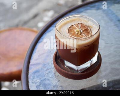 Du café frais à l'orange glacé servi avec des tranches d'orange séchées garnissent la table extérieure du café Banque D'Images