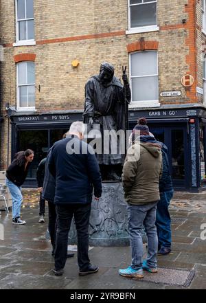 Les touristes admirent la statue de Geoffrey Chaucer, habillé en pèlerin de Canterbury. Le sculpteur de la figure de Chaucer était Sam Holland ARBS, basé dans le Kent, tandis que le concepteur de la grande plinthe, sculptée en bas-relief, était Lynn O'Dowd, basée dans le Yorkshire. Il est situé à l'angle de Best Lane et High Street. Canterbury est une ville et site du patrimoine mondial de l'UNESCO, dans le comté de Kent, en Angleterre ; il a été un arrondissement de comté jusqu'en 1974. Il se trouve sur la rivière Stour. Banque D'Images