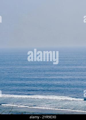 L'horizon calme de l'océan s'étend à l'infini, où le bleu tranquille de la mer rencontre les délicates teintes pastel du ciel. Les vagues douces ondulent doucement u Banque D'Images