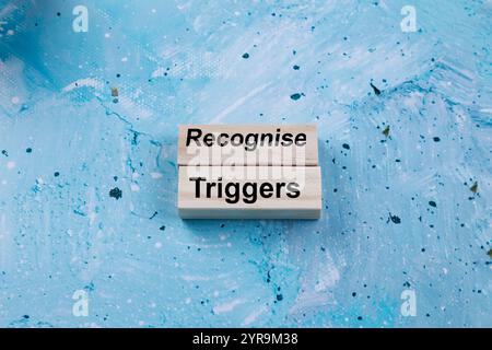 Reconnaître le symbole des déclencheurs. Les mots conceptuels reconnaissent les déclencheurs sur les blocs de bois. Beau fond bleu. Concept des déclencheurs commerciaux et de reconnaissance. Copier Banque D'Images