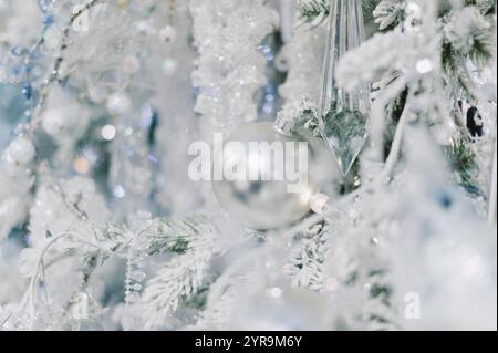 Un arbre avec une boule d'argent dessus. La balle est entourée de neige. Il y a aussi d'autres boules sur l'arbre Banque D'Images