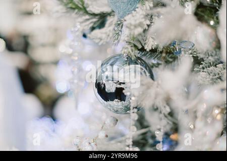 Un arbre avec une boule d'argent dessus. La balle est entourée de neige. Il y a aussi d'autres boules sur l'arbre Banque D'Images