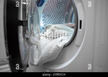Sécheuse ouverte pleine de vêtements blancs. Gros plan. Vue de face. Banque D'Images