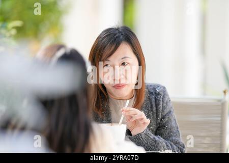 Une femme singapourienne de 40 ans boit du chocolat chaud tout en discutant avec sa fille de 9 ans dans un charmant café sur le thème de Noël dans le centre-ville de Shan Banque D'Images