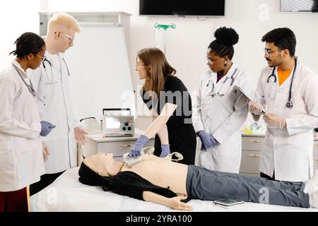 Une femme allongée sur un lit tandis qu'un groupe de médecins se tient autour d'elle, discutant de son état de santé et des options de traitement. Banque D'Images