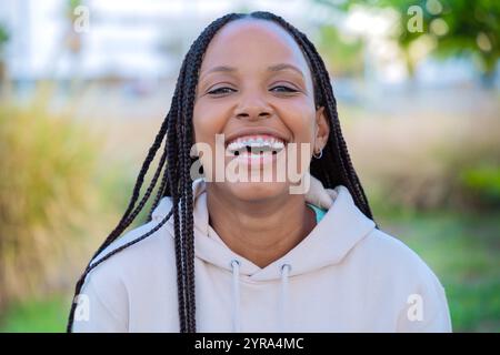 Portrait d'une jeune femme souriante avec des tresses à l'extérieur dans un cadre naturel Banque D'Images