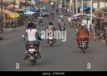 Rue urbaine animée au Togo avec des motos, des piétons et des magasins locaux illustrant la vie quotidienne africaine Banque D'Images